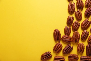Tasty pecan nuts on yellow background, flat lay. Space for text