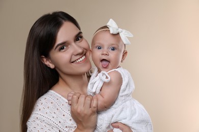 Photo of Beautiful mother with her cute baby on beige background