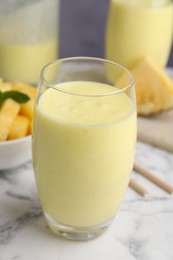 Tasty pineapple smoothie on white marble table, closeup