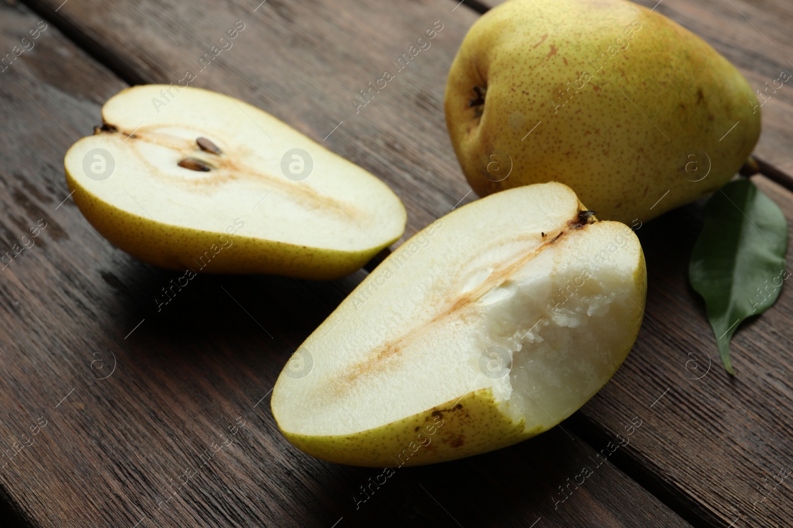 Photo of Whole and halves of tasty fresh pears on wooden table, closeup