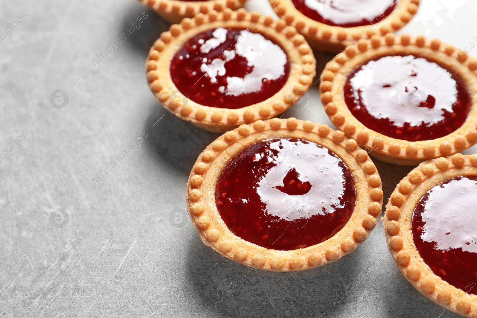 Photo of Tasty tartlets with jam on grey background, closeup