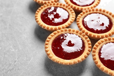 Tasty tartlets with jam on grey background, closeup