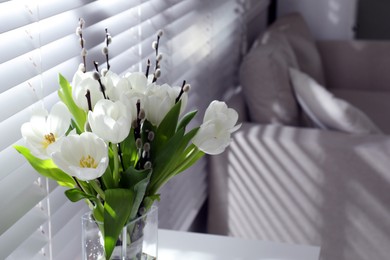 Photo of Beautiful bouquet of willow branches and tulips in vase near window indoors, space for text