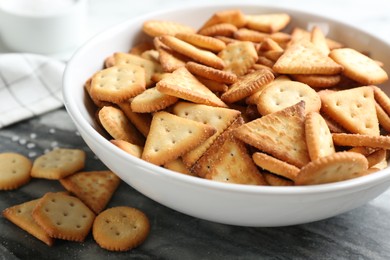 Photo of Delicious crispy crackers on dark board, closeup