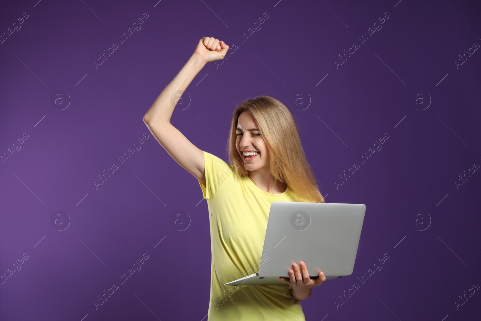 Photo of Portrait of emotional woman with modern laptop on purple background