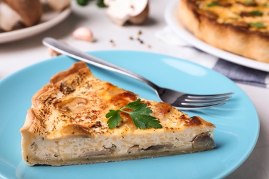 Delicious pie with mushrooms and cheese on light blue plate, closeup