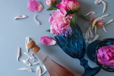 Photo of Flat lay composition with bottle of rose wine, glasses and beautiful pink peonies on grey background