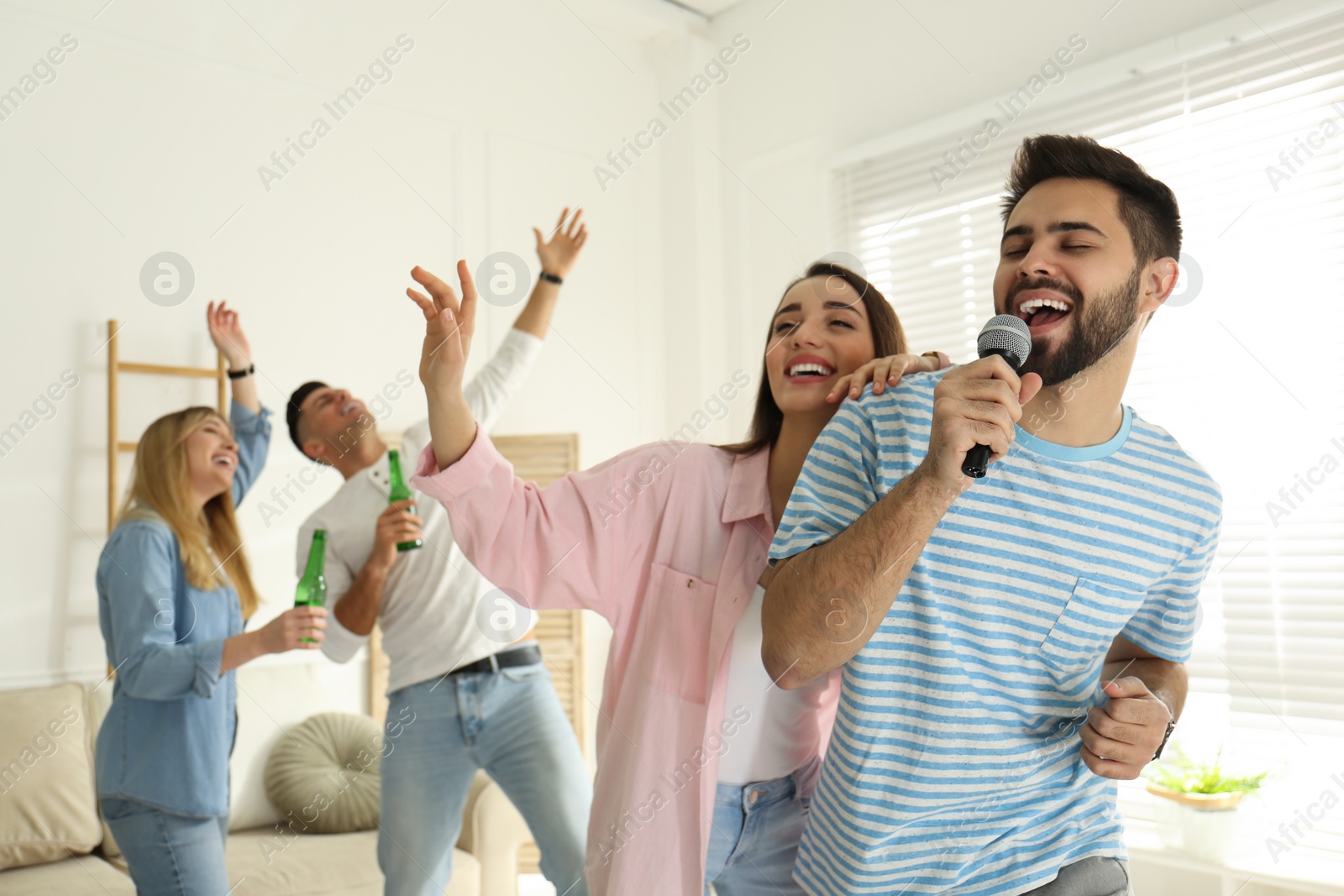 Photo of Young man singing karaoke with friends at home