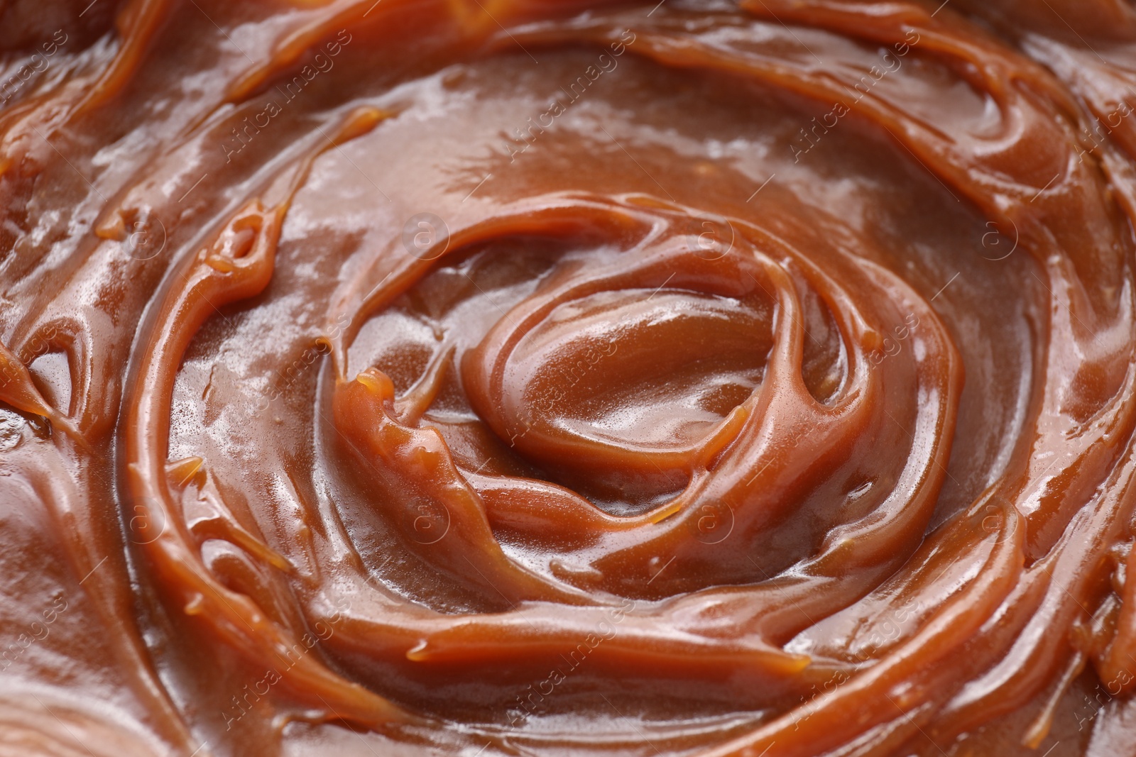 Photo of Tasty sweet caramel sauce as background, above view