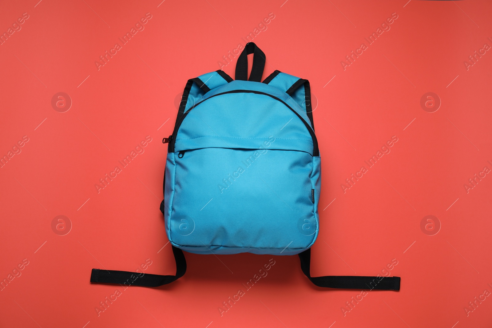 Photo of Stylish light blue backpack on red background, top view