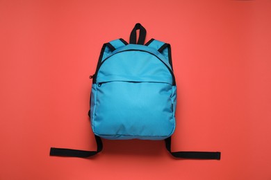 Stylish light blue backpack on red background, top view