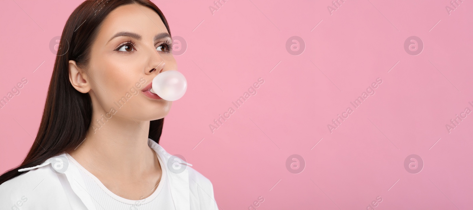 Photo of Beautiful woman blowing bubble gum on pink background, space for text