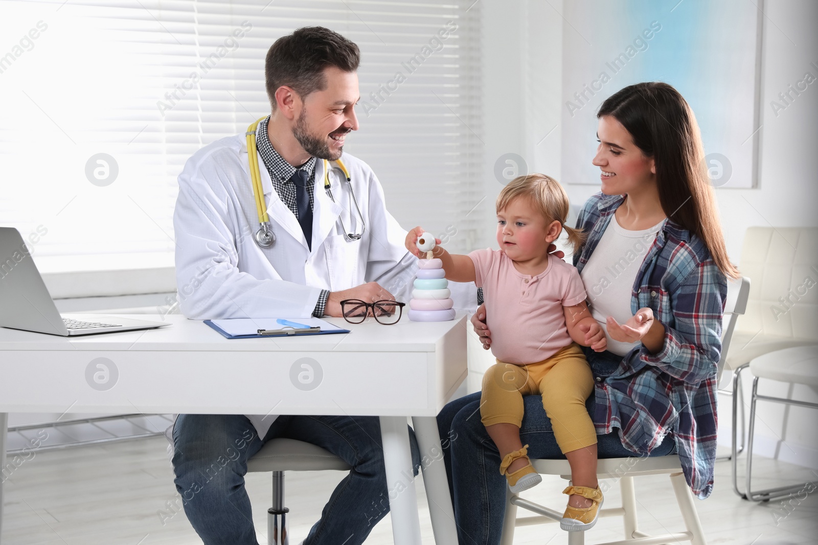 Photo of Mother and her cute baby having appointment with pediatrician in clinic. Doctor examining little girl