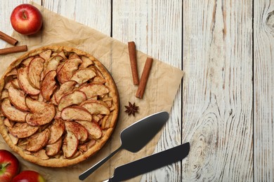 Delicious apple pie and ingredients on white wooden table, flat lay. Space for text