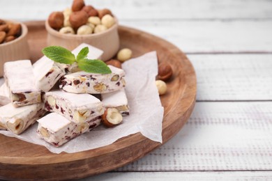 Photo of Pieces of delicious nougat and nuts on wooden board, closeup