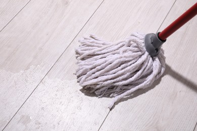 Cleaning dirty wooden floor with mop indoors