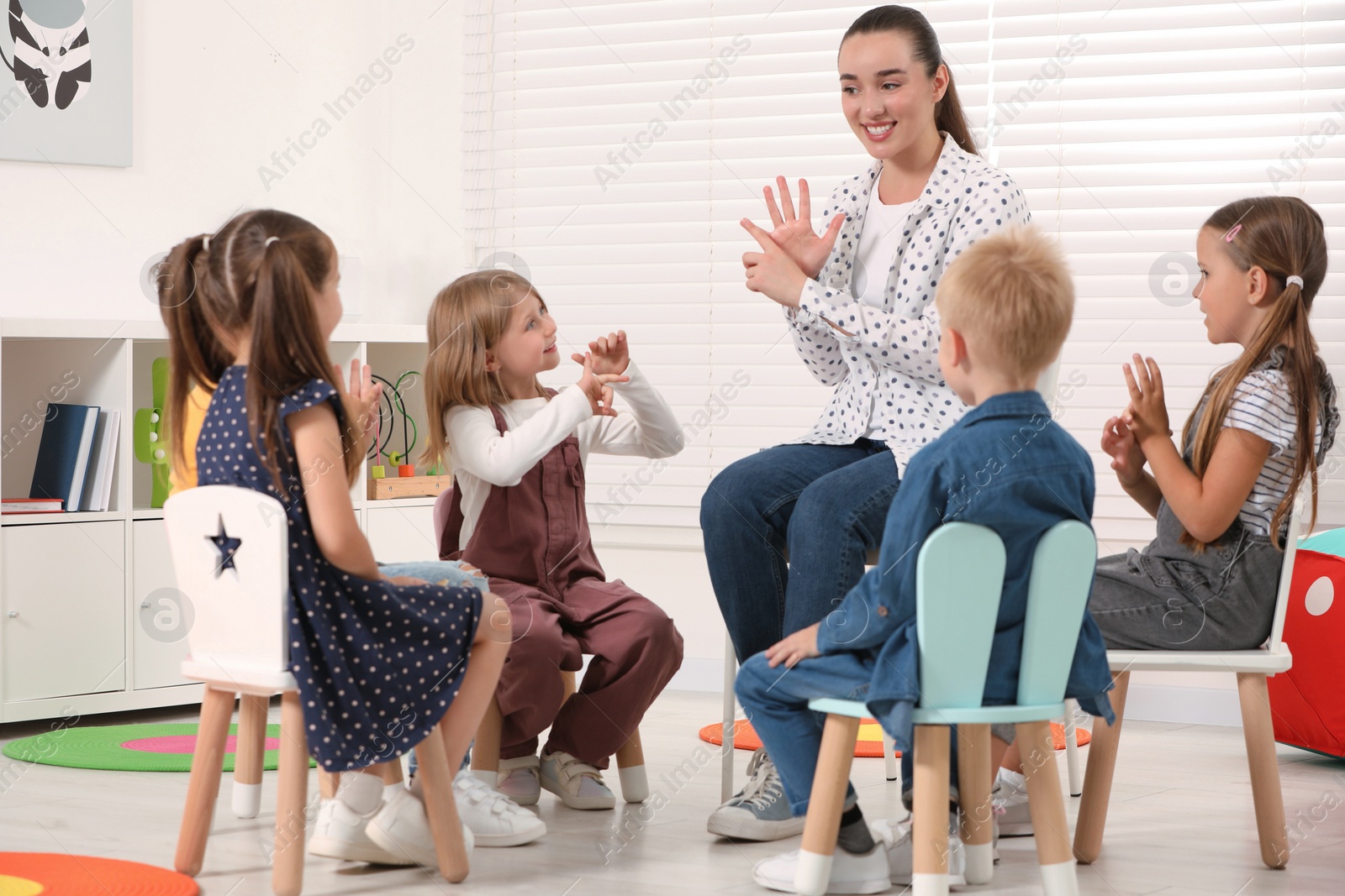 Photo of Nursery teacher and group of cute little children learning numbers in kindergarten. Playtime activities