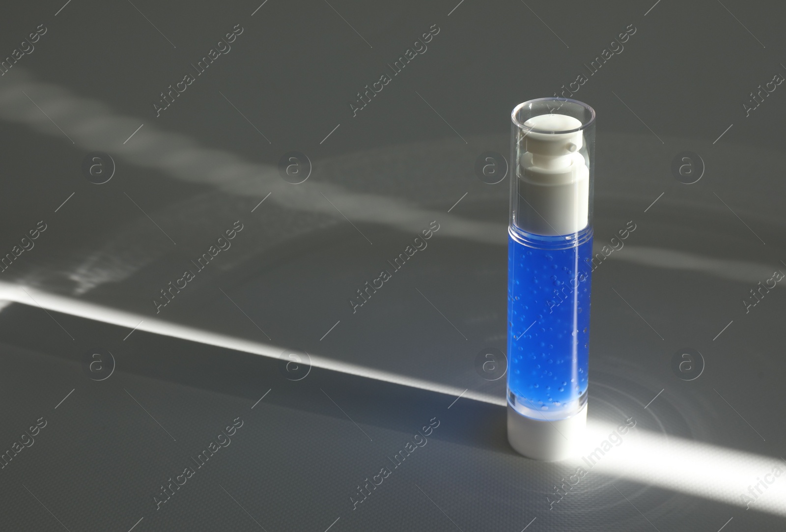 Photo of Bottle of cosmetic product on grey table. Space for text