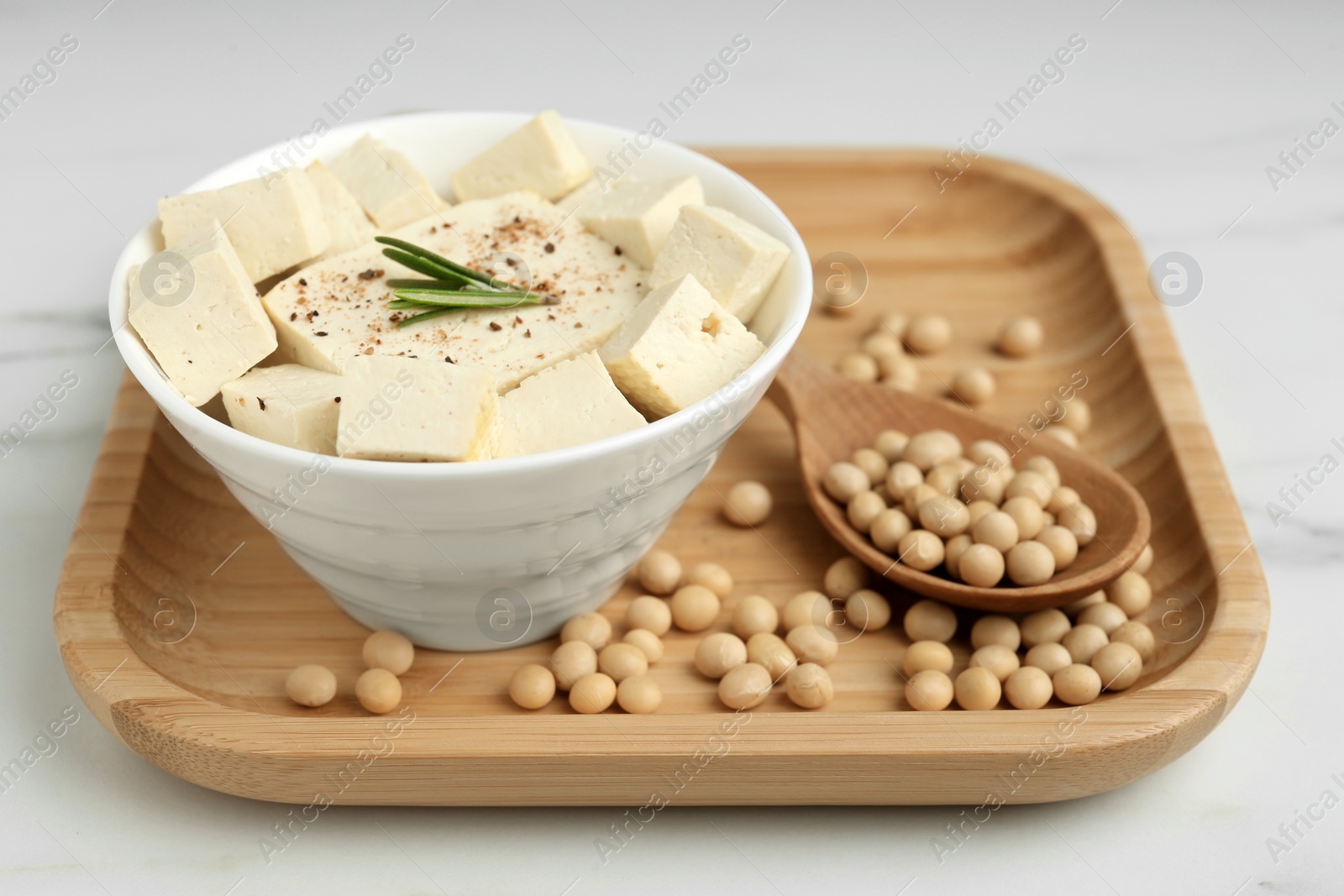 Photo of Pieces of delicious tofu with rosemary and soy on white wooden table