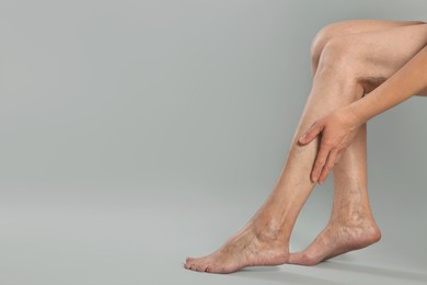 Photo of Closeup view of woman suffering from varicose veins on light grey background. Space for text
