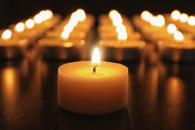 Wax candle burning on table in darkness, closeup