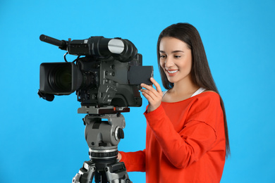 Operator with professional video camera on blue background