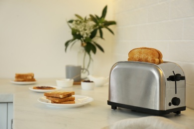 Modern toaster and tasty breakfast on counter in kitchen