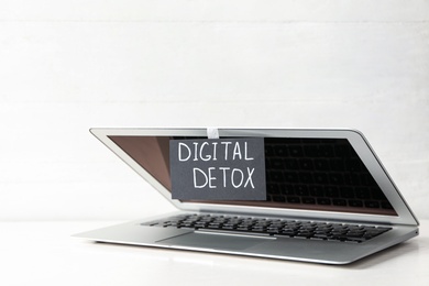 Photo of Laptop and paper with words DIGITAL DETOX on white wooden table
