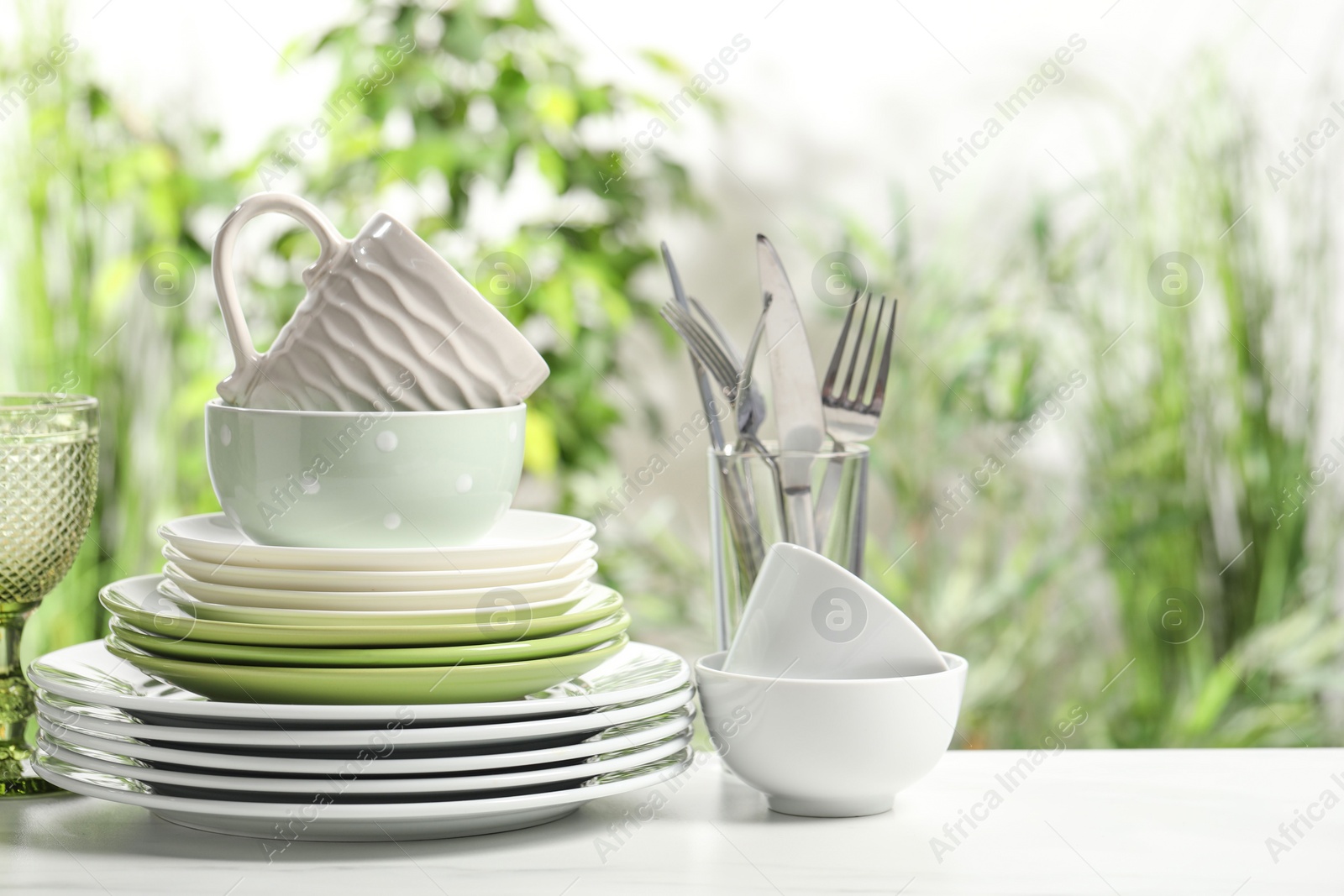Photo of Beautiful ceramic dishware, cutlery and cup on white table outdoors, space for text
