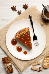 Tasty cheesecake with caramel and nuts served on white wooden table, flat lay