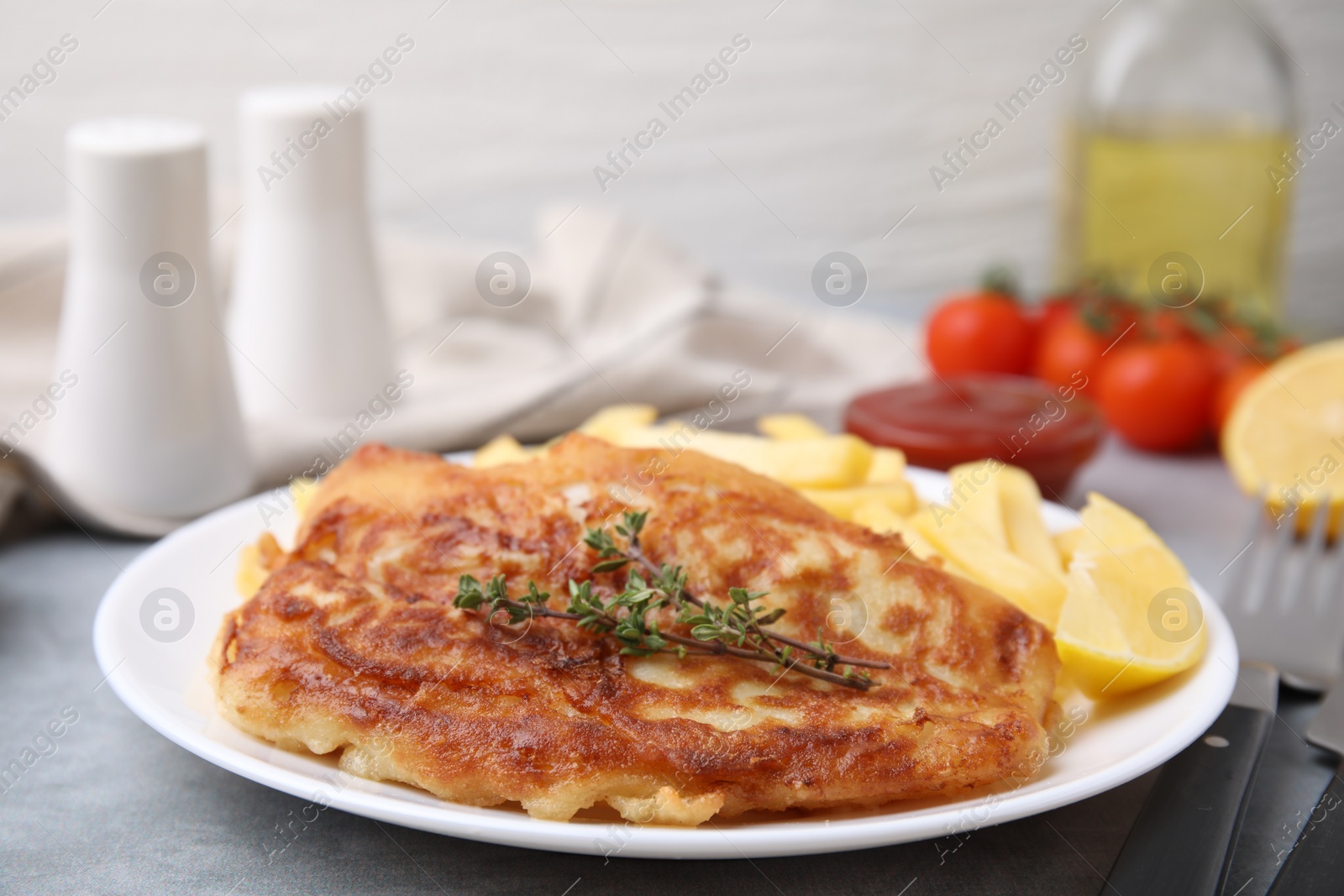 Photo of Tasty soda water battered fish, potato chips and lemon slice on light grey table