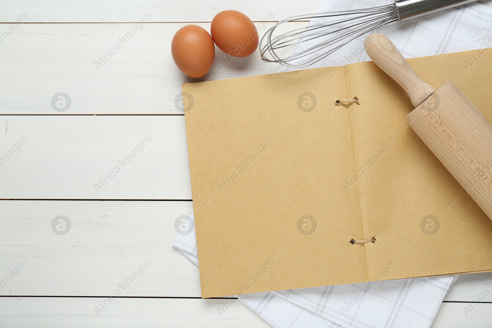 Photo of Blank recipe book, kitchen utensils and eggs on white wooden table, flat lay. Space for text