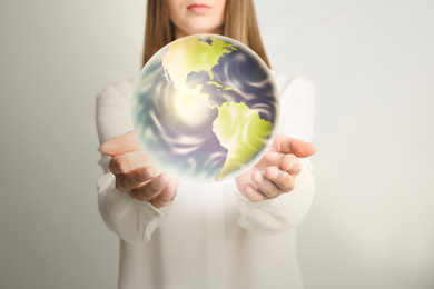 Image of Woman holding Earth on light background, closeup