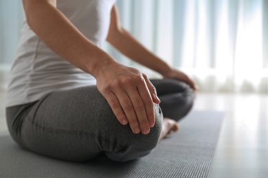 Photo of Woman practicing yoga on floor indoors, closeup. Space for text