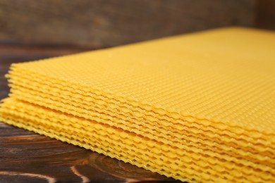Photo of Natural beeswax sheets on wooden table, closeup