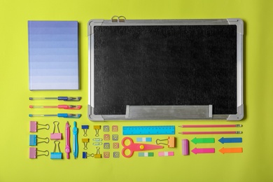 Photo of Flat lay composition with different school stationery and small chalkboard on color background