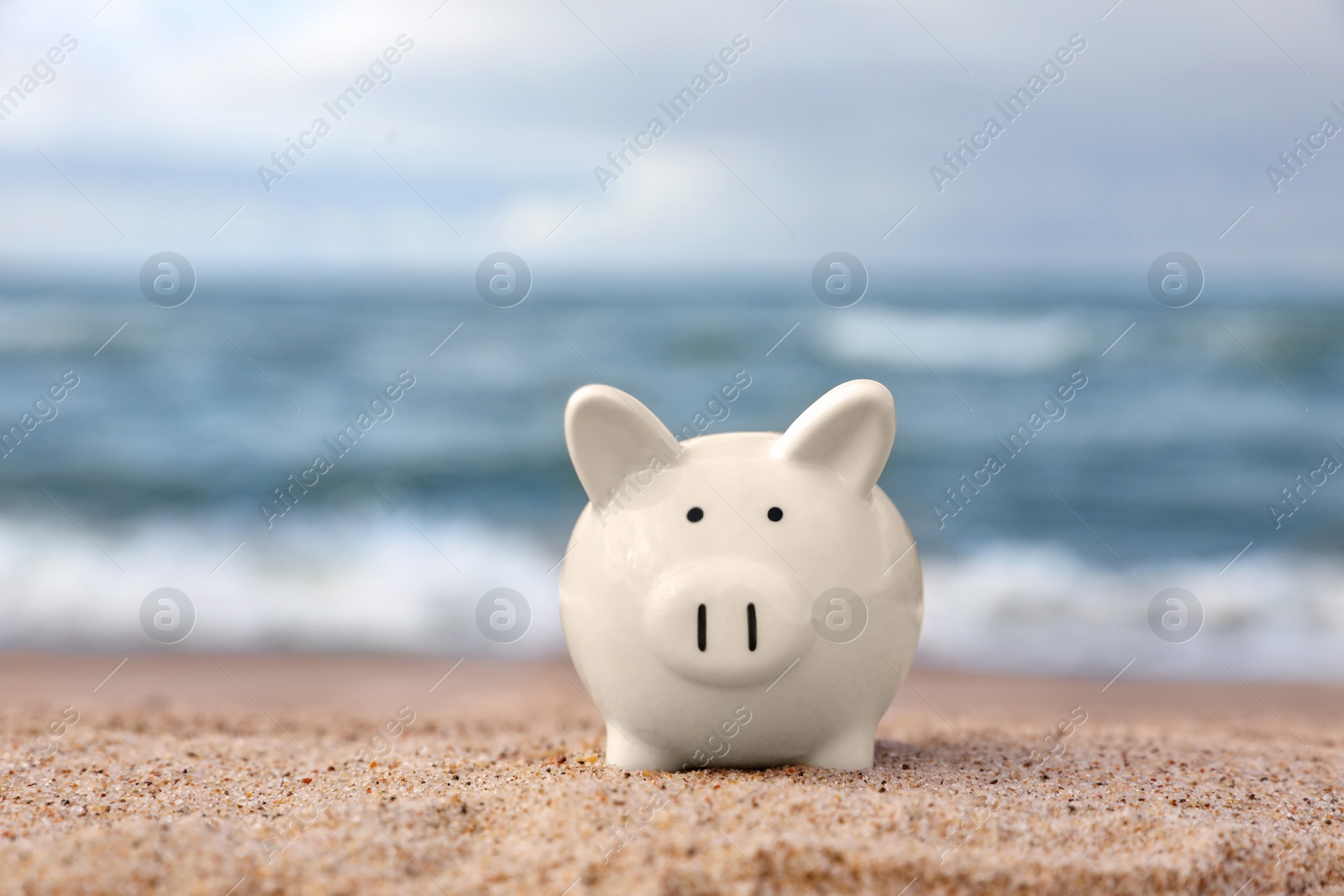 Photo of Cute piggy bank on sand near sea