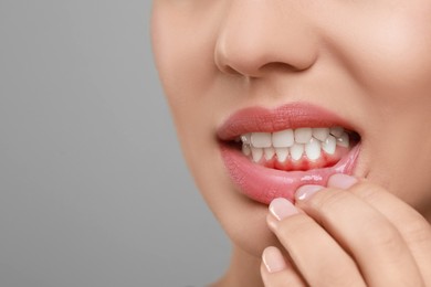 Image of Woman showing inflamed gum on grey background, closeup. Space for text