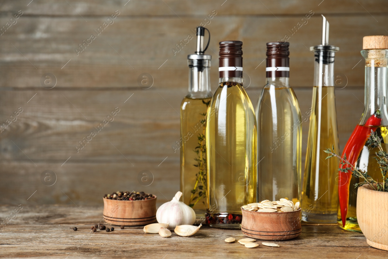 Photo of Different cooking oils in bottles on wooden table