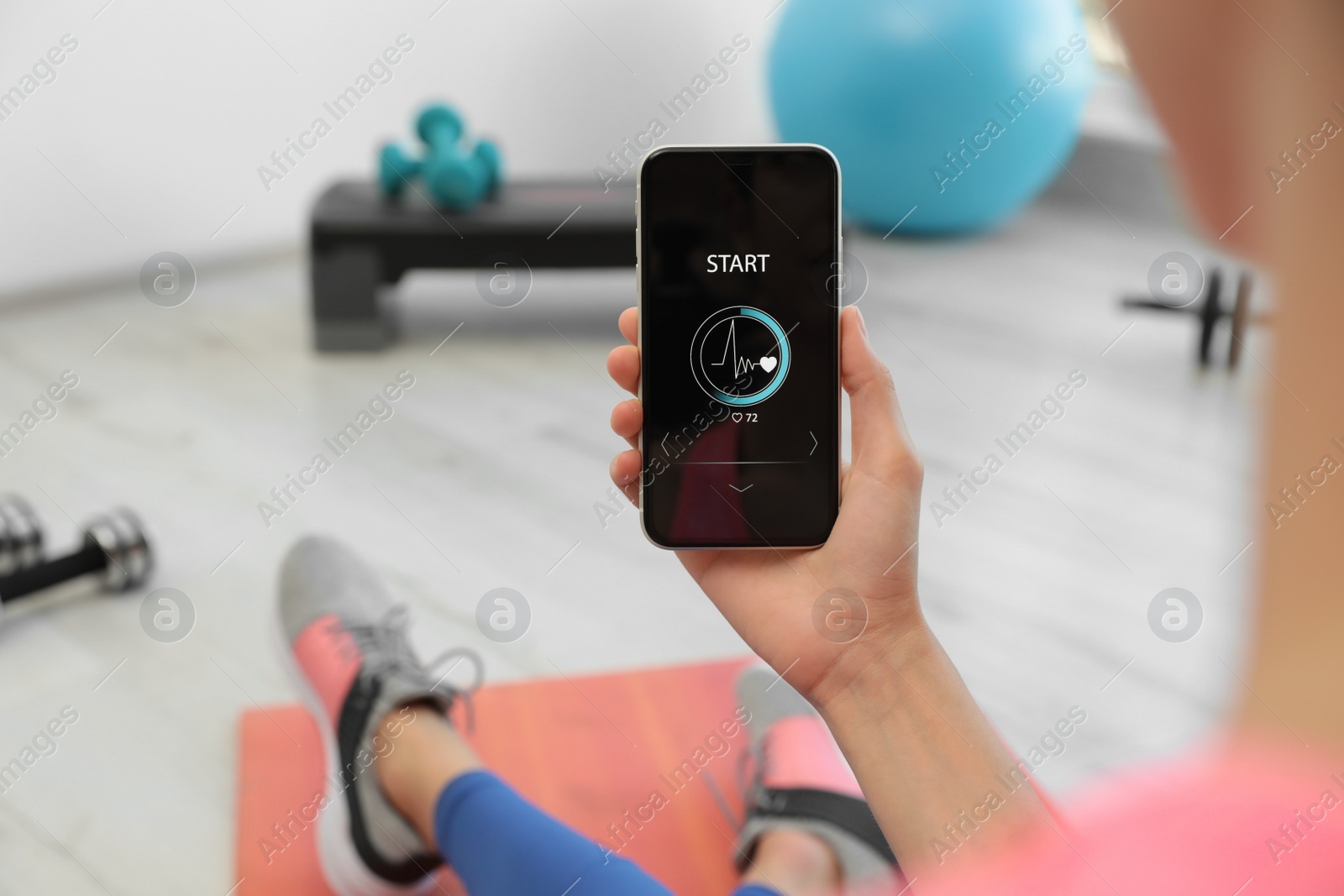 Photo of Young woman using fitness app on smartphone indoors, closeup