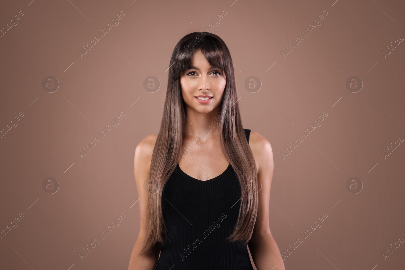 Image of Attractive woman with shiny straight hair on brown background. Professional hairstyling