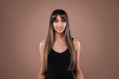 Image of Attractive woman with shiny straight hair on brown background. Professional hairstyling