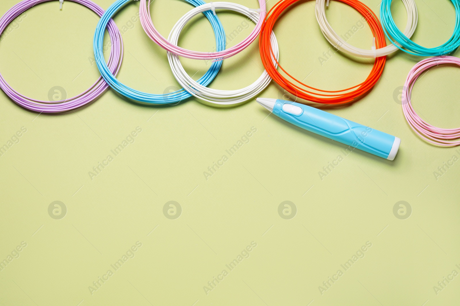 Photo of Stylish 3D pen and colorful plastic filaments on olive background, flat lay. Space for text