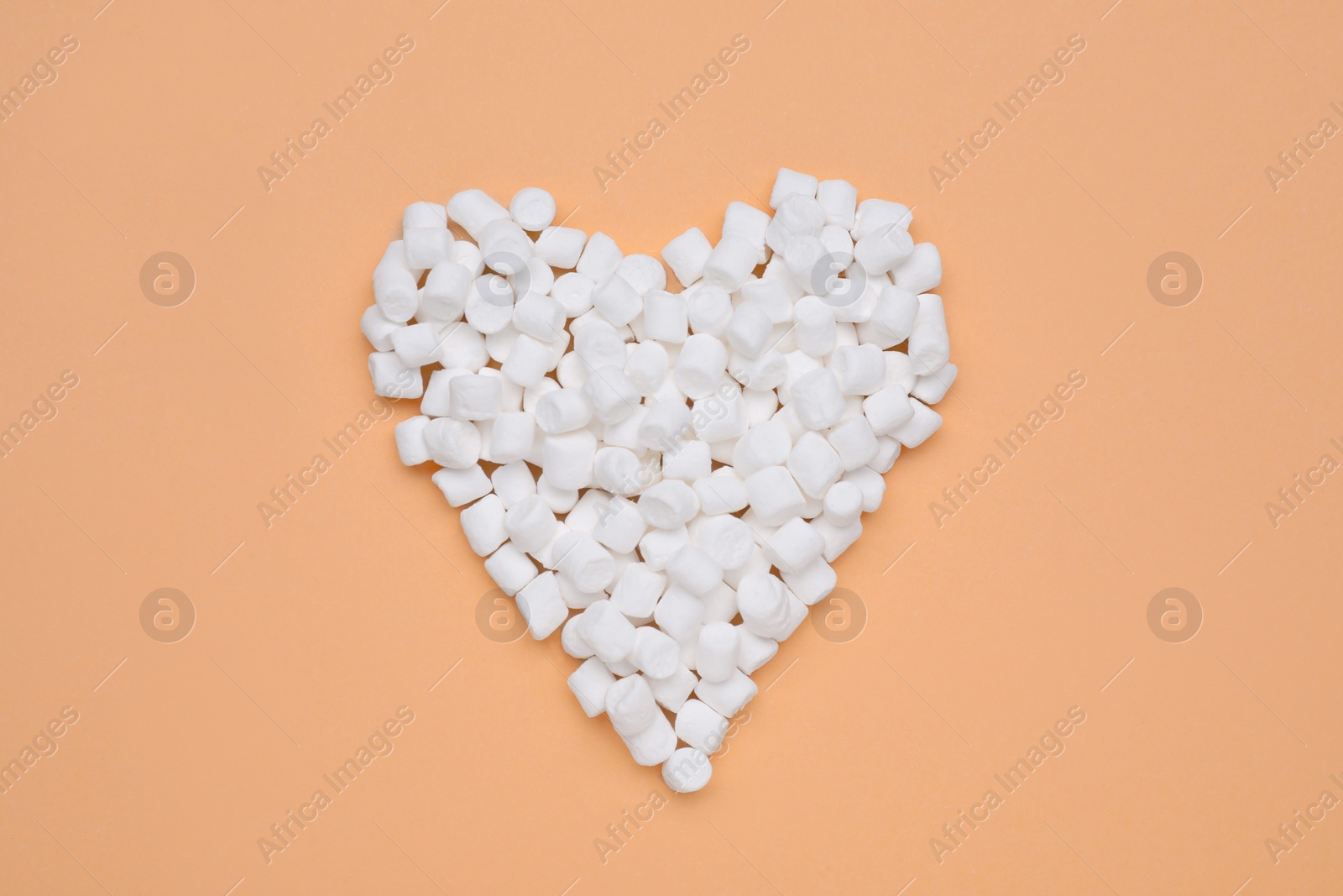 Photo of Heart made of sweet marshmallows on orange background, top view