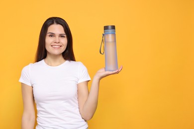 Photo of Young woman with bottle of water on orange background. Space for text