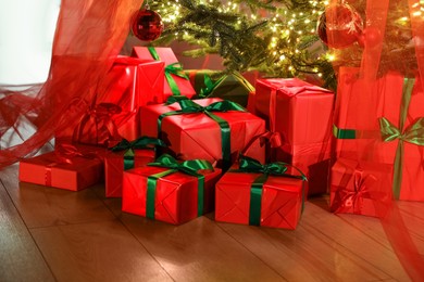 Photo of Beautifully wrapped gift boxes under Christmas tree indoors