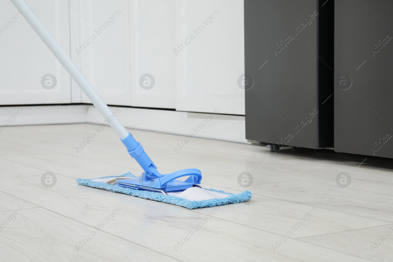 Photo of Cleaning of parquet floor with mop indoors