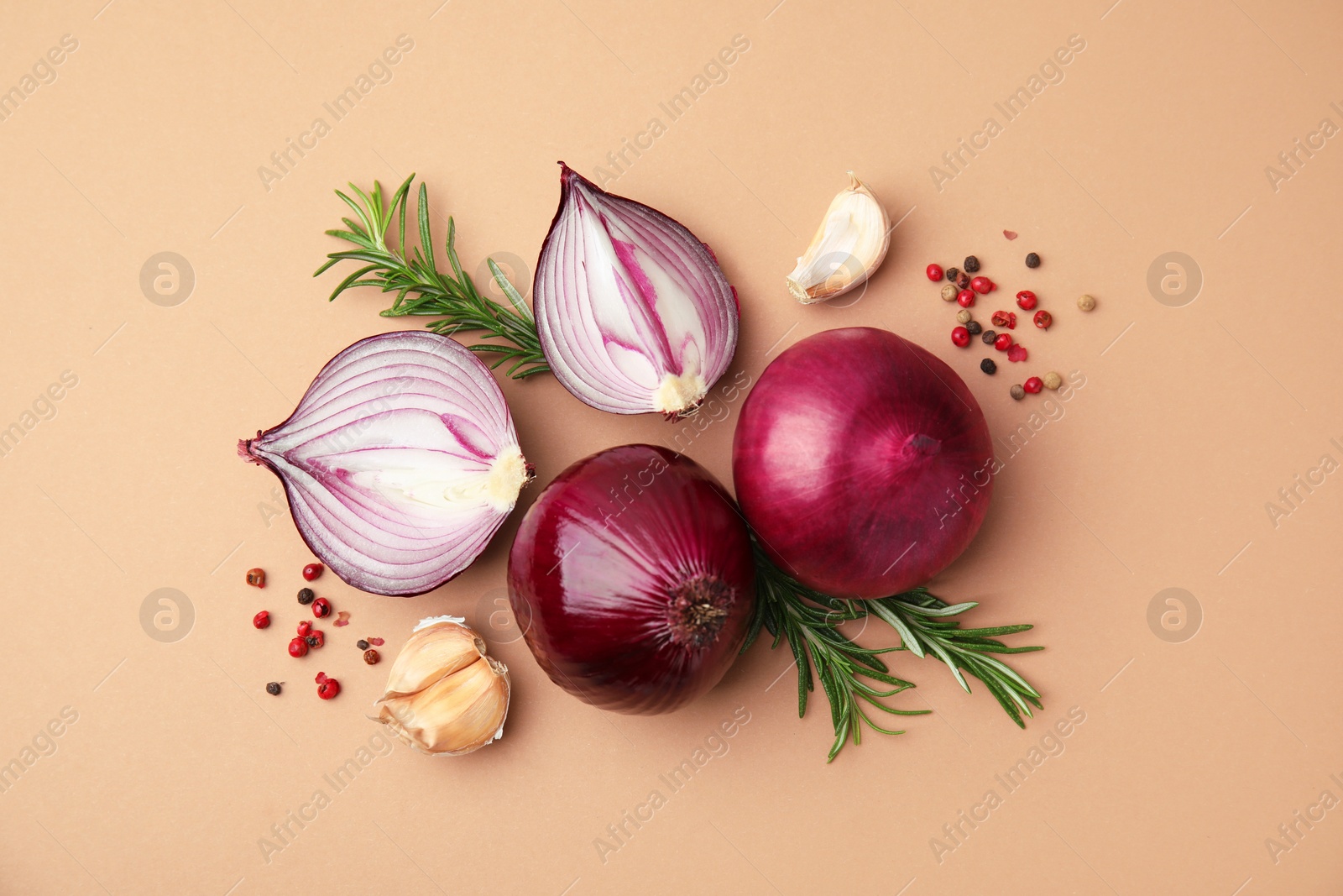 Photo of Fresh red onions, garlic, rosemary and spices on beige background, flat lay