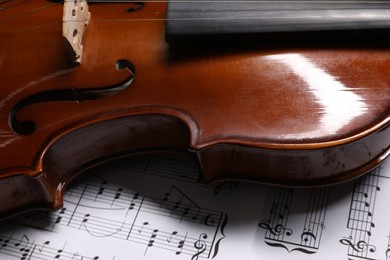 Photo of Classic violin on music sheets, closeup view