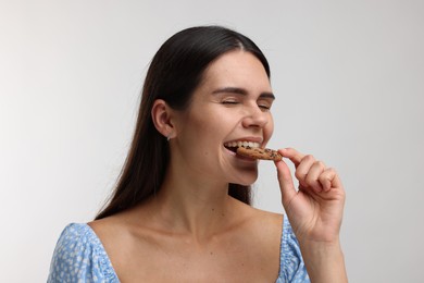 Young woman with chocolate chip cookie on white background